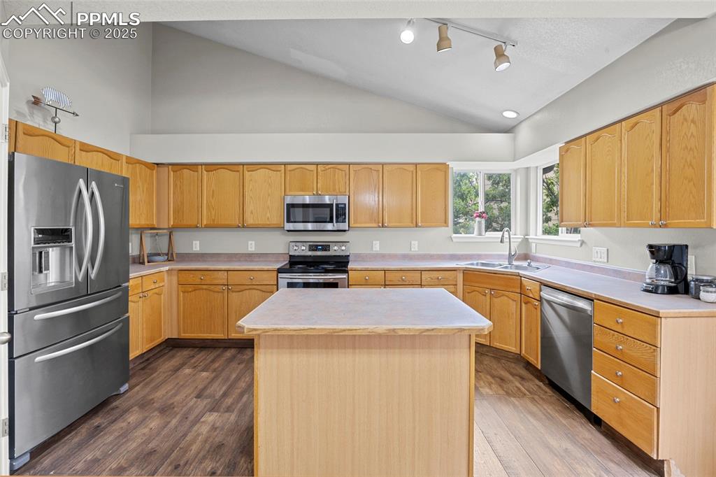 Image 15 of 50: Kitchen featuring light countertops, vaulted ceiling, stainless steel appli