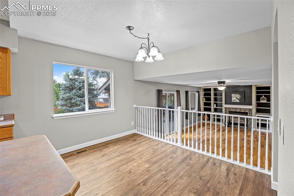 Image 17 of 50: Unfurnished dining area with a fireplace, a textured ceiling, light wood-st