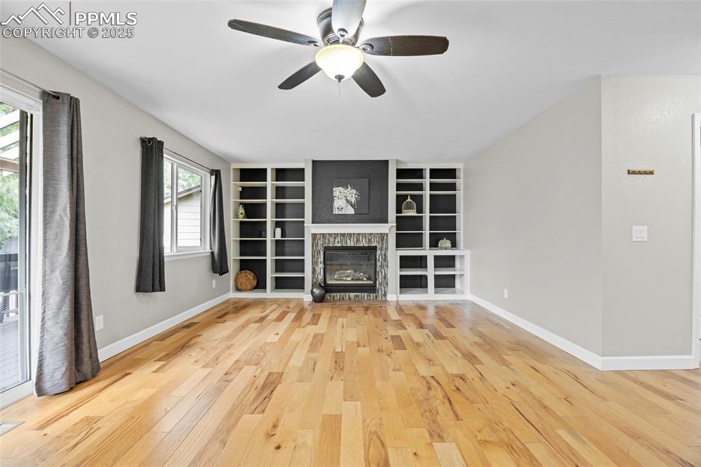 Image 20 of 50: Unfurnished living room featuring light wood-style floors, ceiling fan, bui