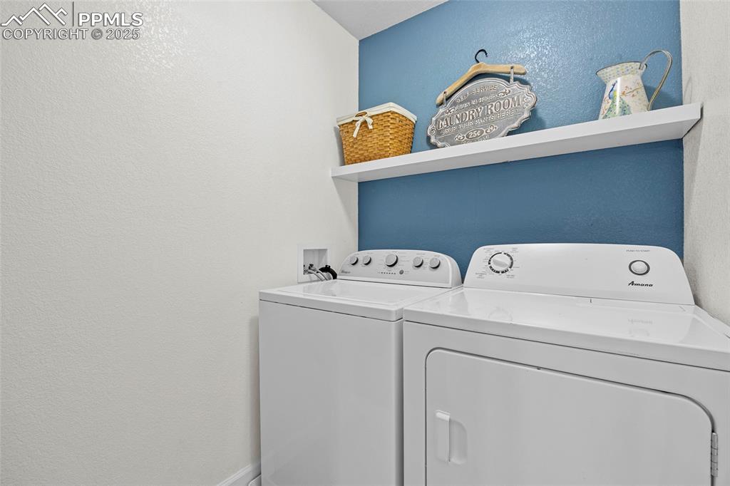 Image 23 of 50: Washroom with a textured wall and washing machine and clothes dryer