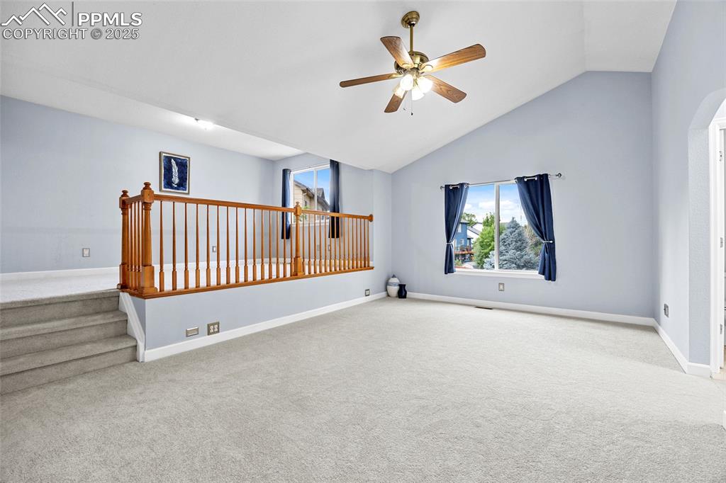Image 24 of 50: Spare room with carpet floors, a ceiling fan, high vaulted ceiling, and arc