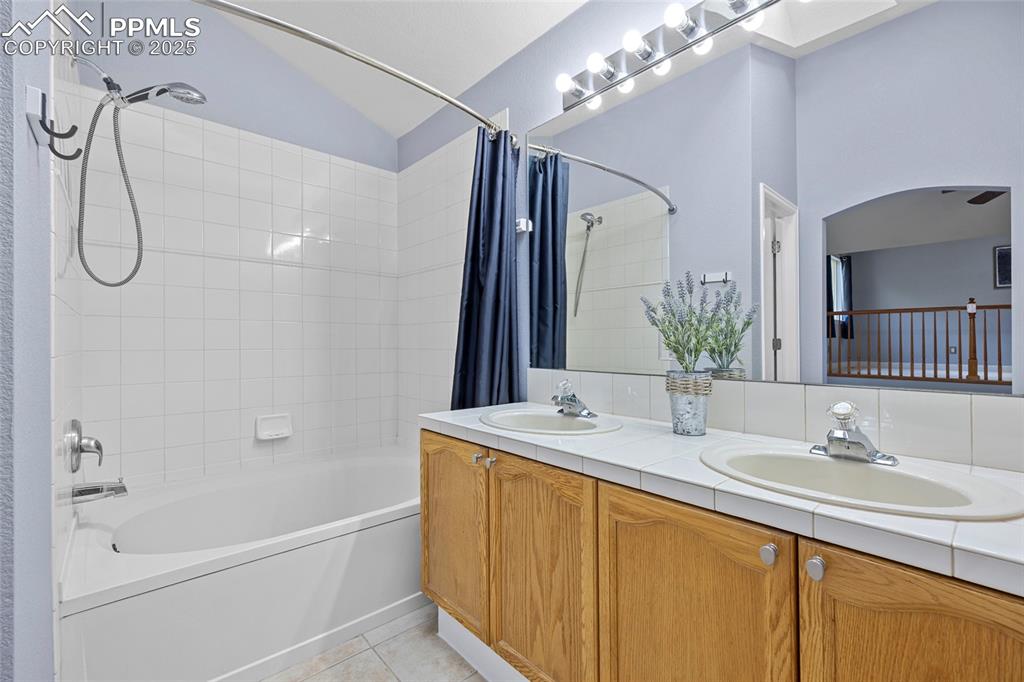 Image 30 of 50: Bathroom with shower / bath combo, light tile patterned floors, double vani