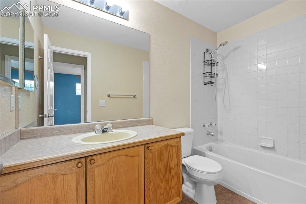Image 34 of 50: Bathroom with tub / shower combination, vanity, dark tile patterned floors,