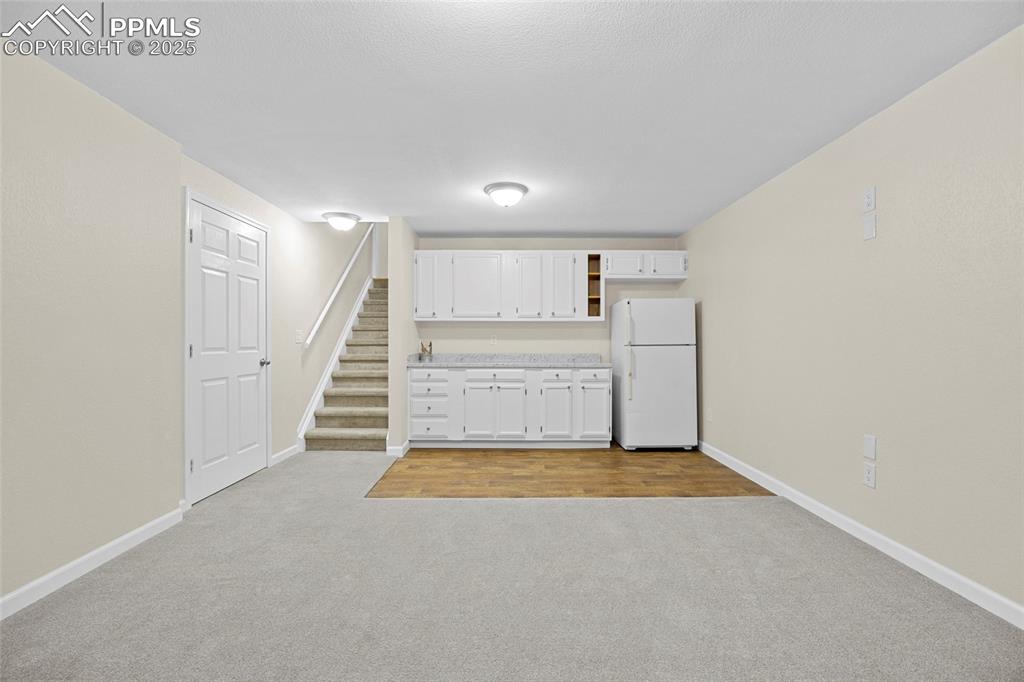 Image 38 of 50: Kitchen with light countertops, freestanding refrigerator, light colored ca