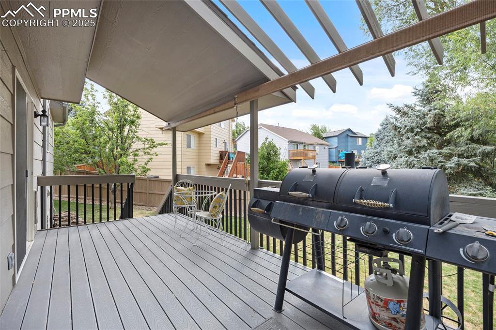 Image 44 of 50: Wooden deck with area for grilling, a residential view, and a pergola