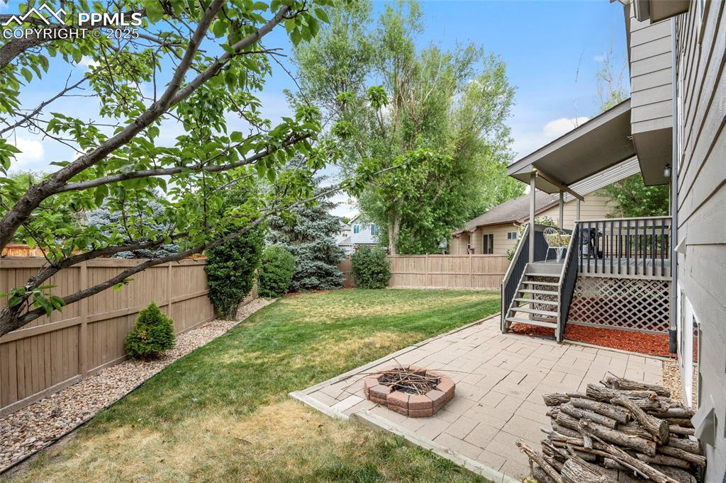 Image 46 of 50: Fenced backyard with a patio, an outdoor fire pit, a wooden deck, and stair