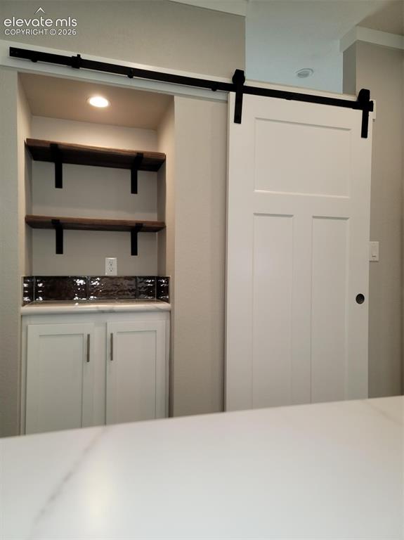 Image 10 of 41: Built-in cabinetry with countertop, dark backsplash, recessed lighting, an