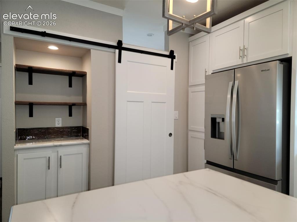 Image 28 of 41: White shaker-style cabinetry, matte black sliding barn door hardware, stain