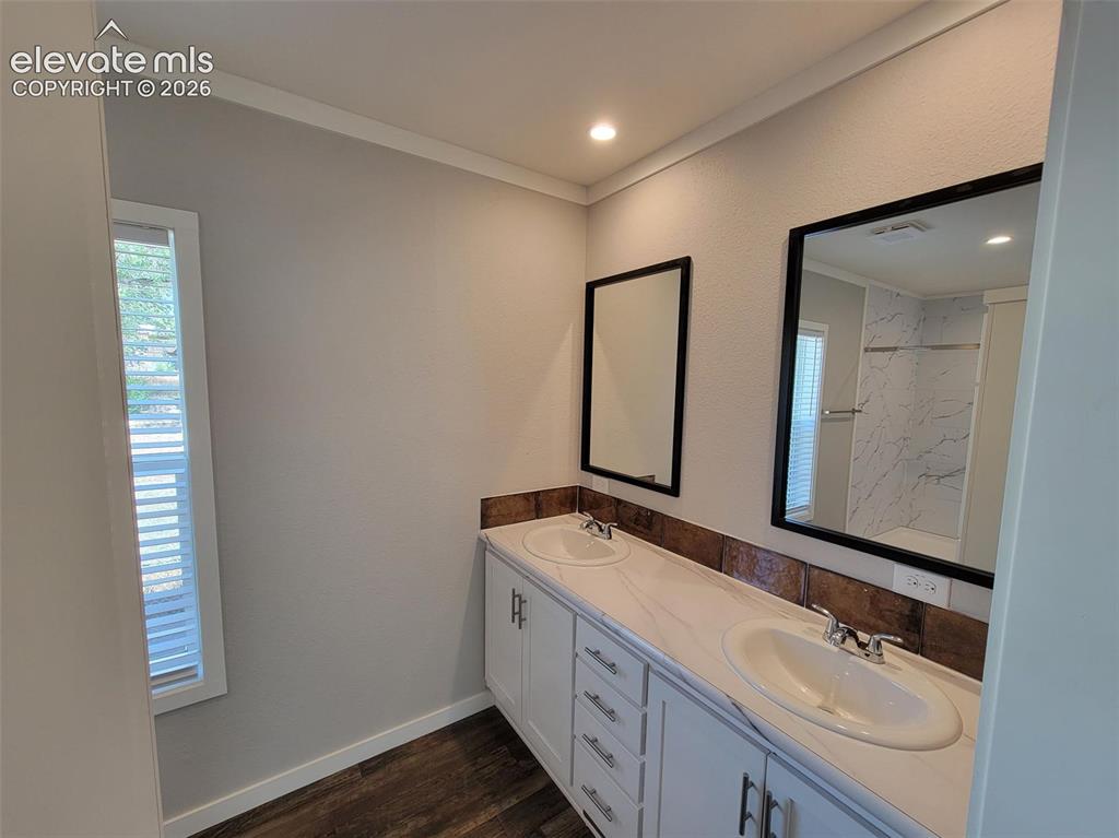 Image 30 of 41: Dual-sink vanity with stone-finish countertop, white cabinetry with metal h