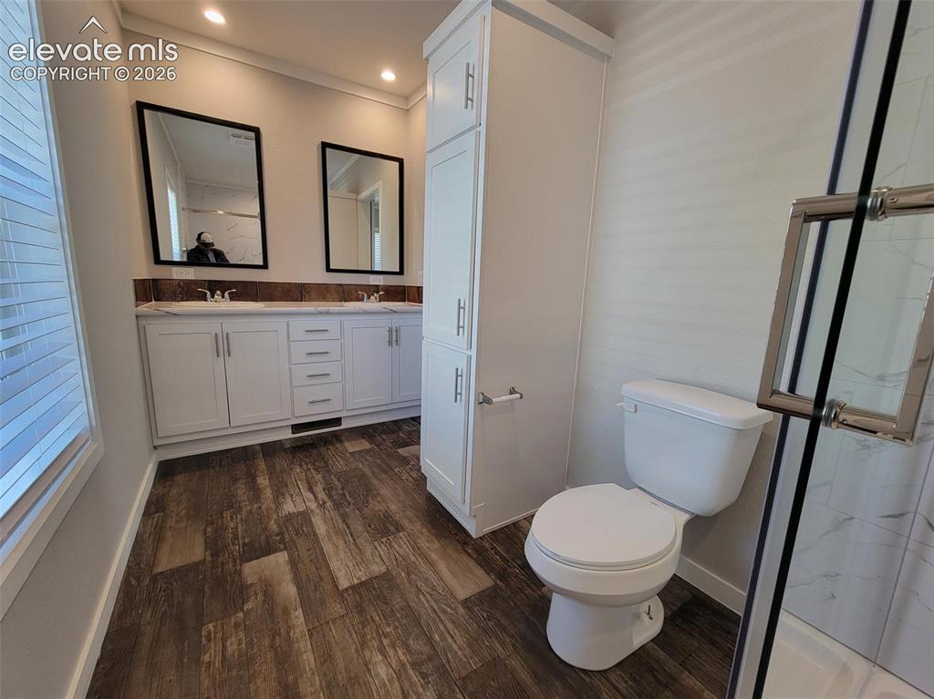 Image 32 of 41: Bathroom featuring a dual-sink vanity with white cabinetry, wood-finish flo