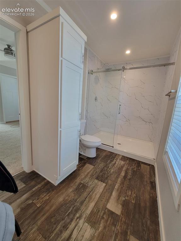 Image 34 of 41: Walk-in shower with sliding glass doors, floor-to-ceiling stone-patterned w
