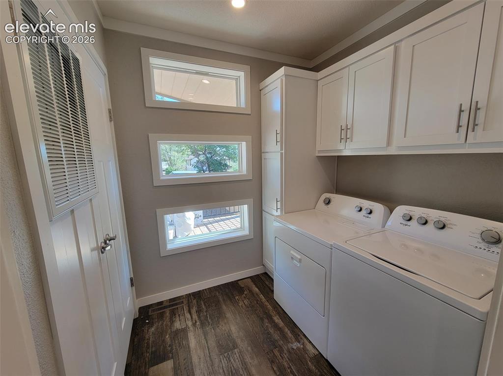 Image 36 of 41: Laundry area featuring white shaker-style wall cabinets and full-height sto