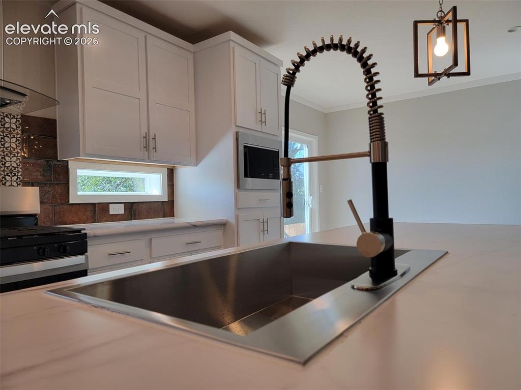 Image 4 of 41: Kitchen featuring white shaker-style cabinetry, an integrated microwave, so
