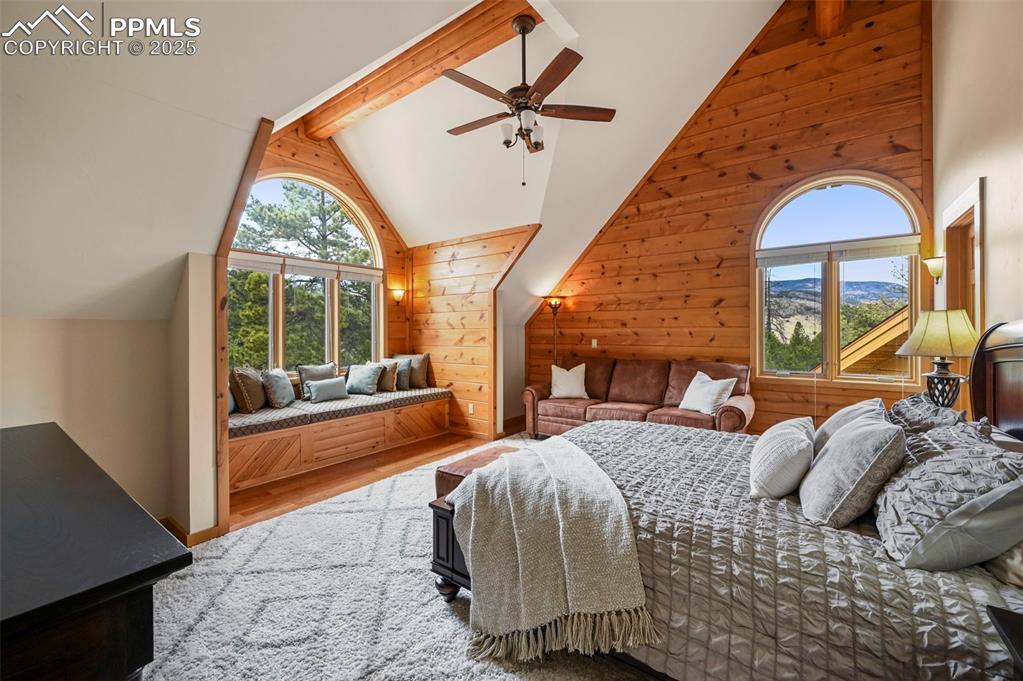 Image 28 of 50: Bedroom with high vaulted ceiling, wooden walls, beam ceiling, and wood fin