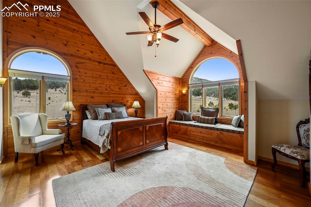Image 29 of 50: Bedroom featuring a ceiling fan, light wood finished floors, wooden walls, 