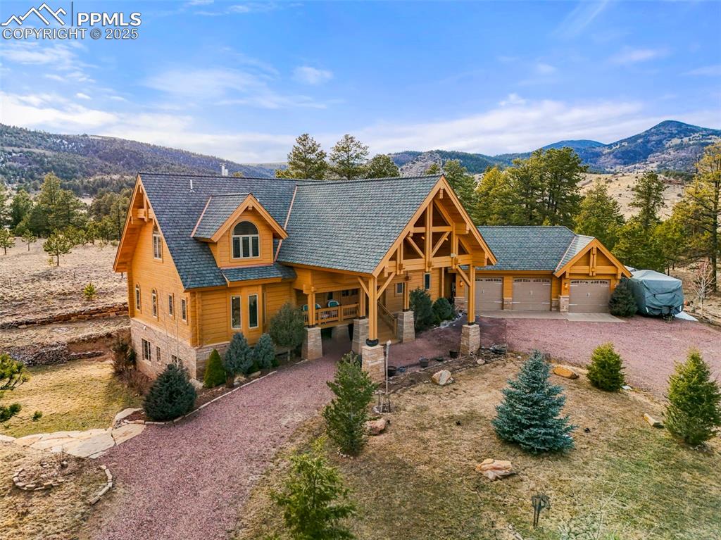 Image 41 of 50: View of front with garage, driveway, stone siding, and a Mountain View