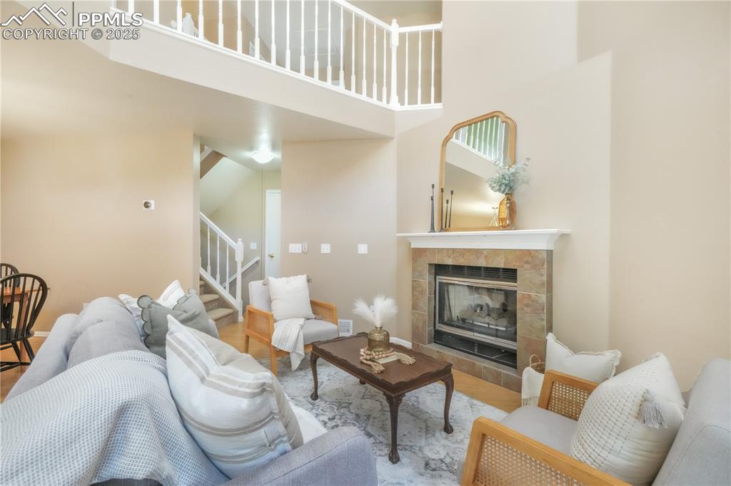 Image 10 of 47: Living area featuring a high ceiling, a tile fireplace, stairway, and wood 