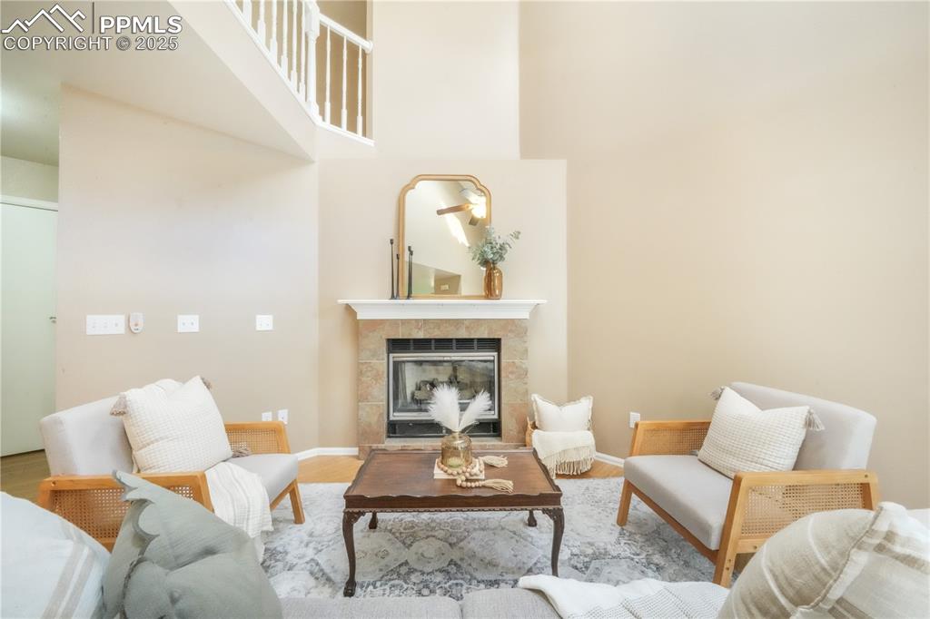 Image 11 of 47: Living area featuring wood finished floors, a tiled fireplace, and a high c