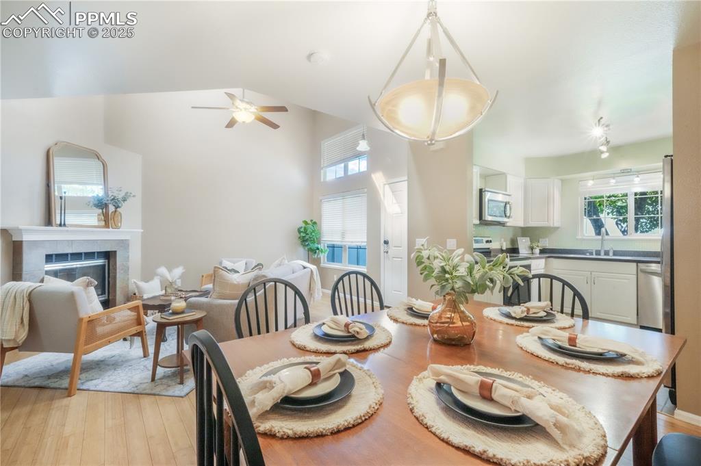Image 14 of 47: Dining area featuring a fireplace, light wood-style floors, ceiling fan, an