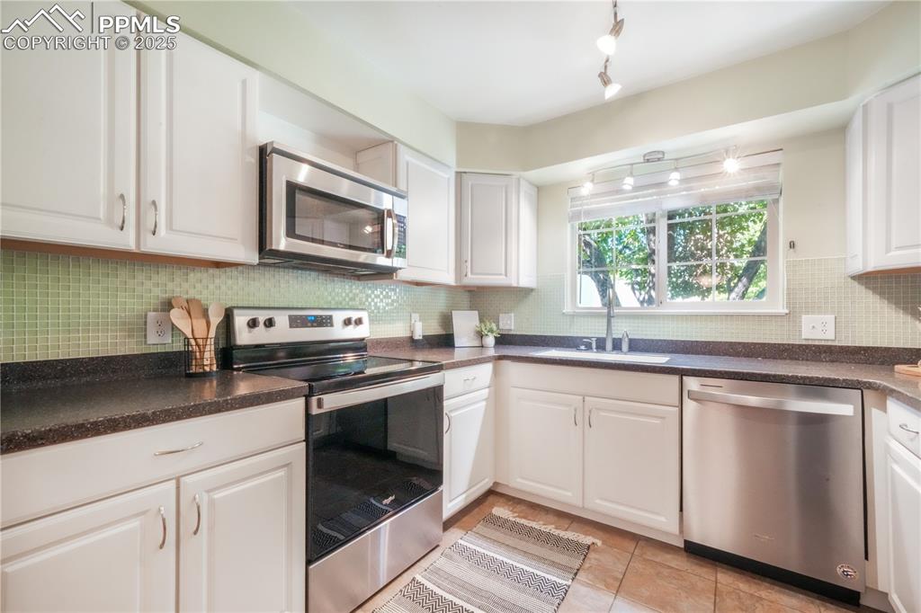 Image 18 of 47: Kitchen with dark countertops, stainless steel appliances, backsplash, and 