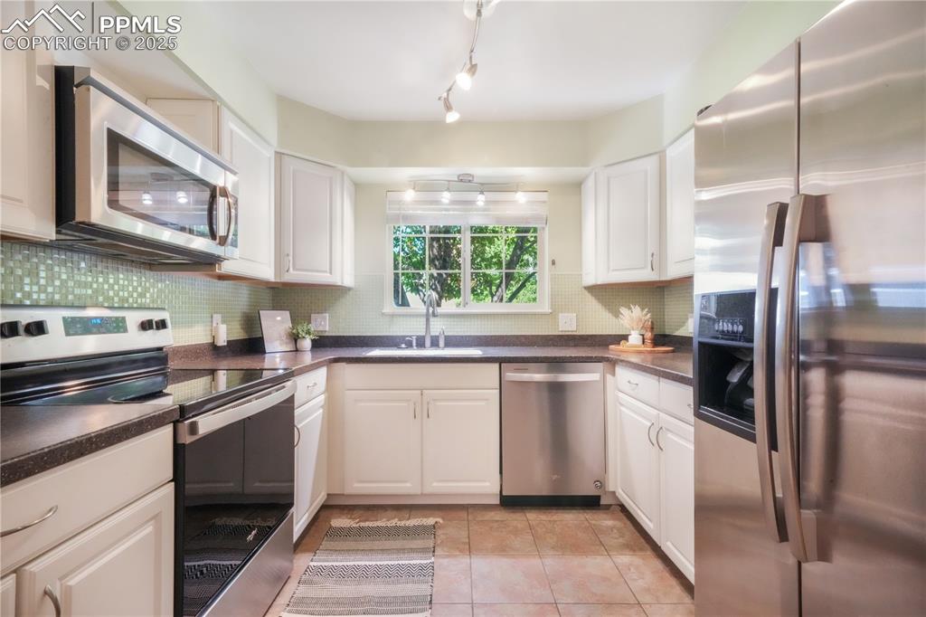 Image 19 of 47: Kitchen with stainless steel appliances, decorative backsplash, white cabin