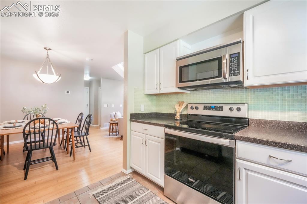Image 20 of 47: Kitchen with stainless steel appliances, dark countertops, white cabinets, 