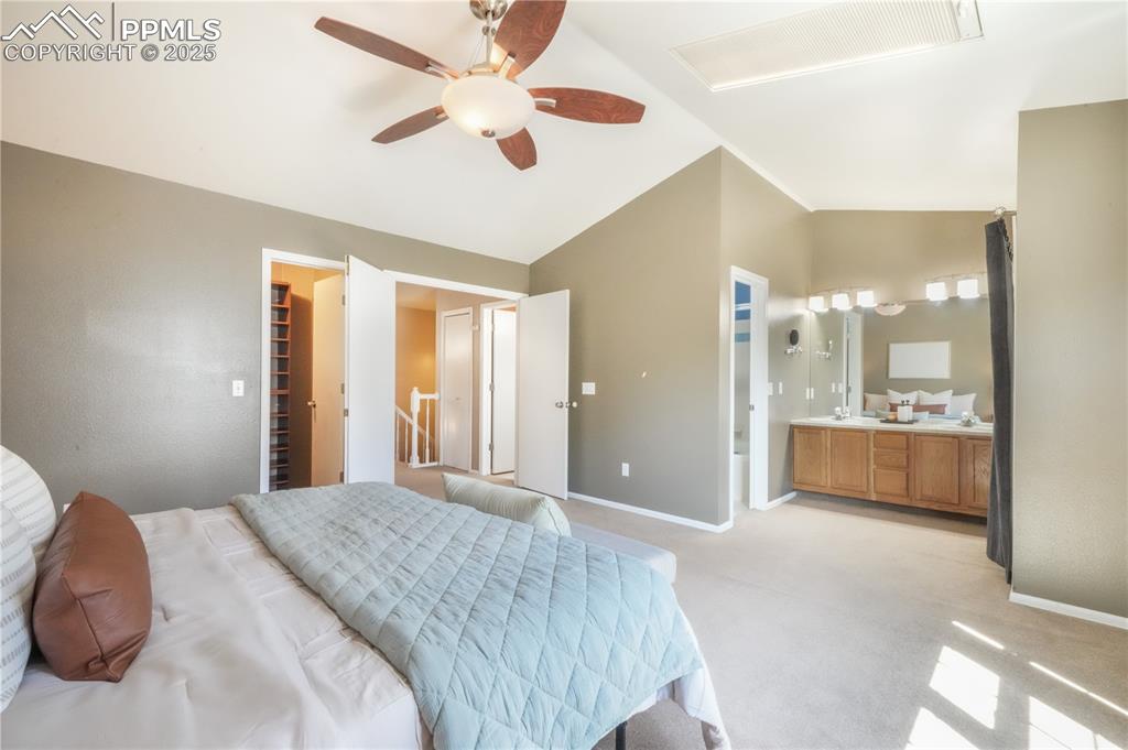 Image 25 of 47: Bedroom featuring vaulted ceiling, a spacious closet, light carpet, ensuite