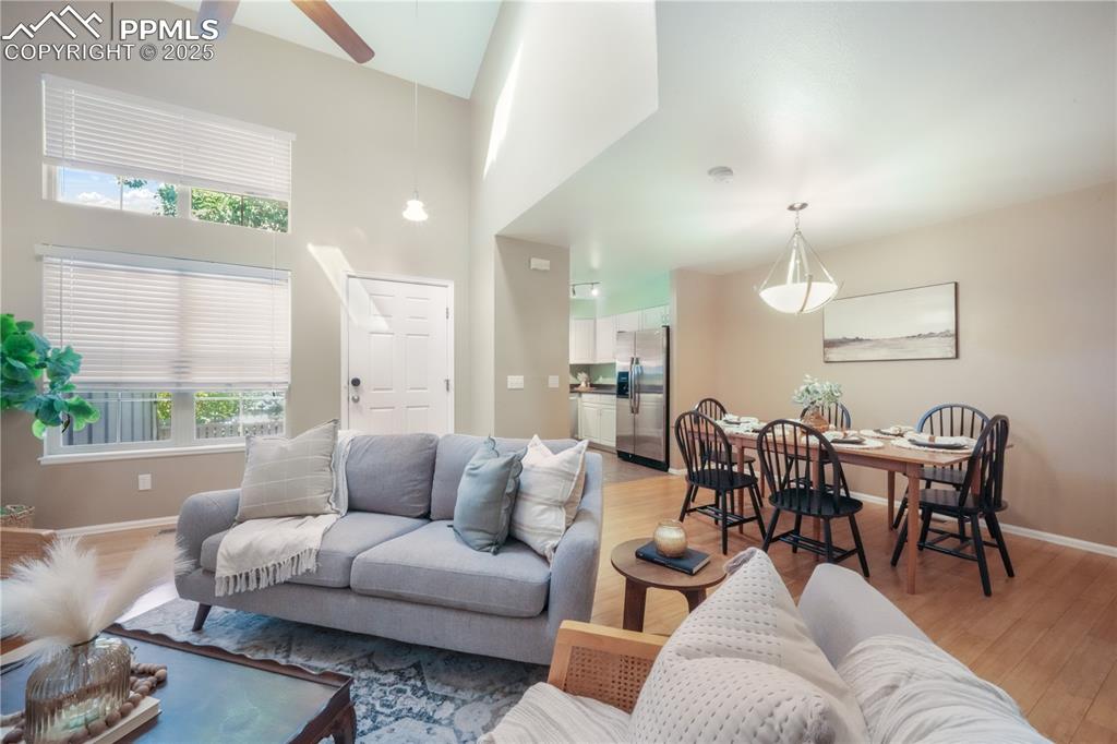 Image 9 of 47: Living room featuring a ceiling fan, a towering ceiling, and light wood fin