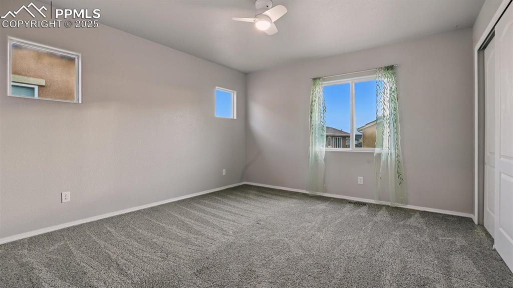 Image 32 of 50: Upper Level Bedroom #2 with neutral carpet and ceiling fan.