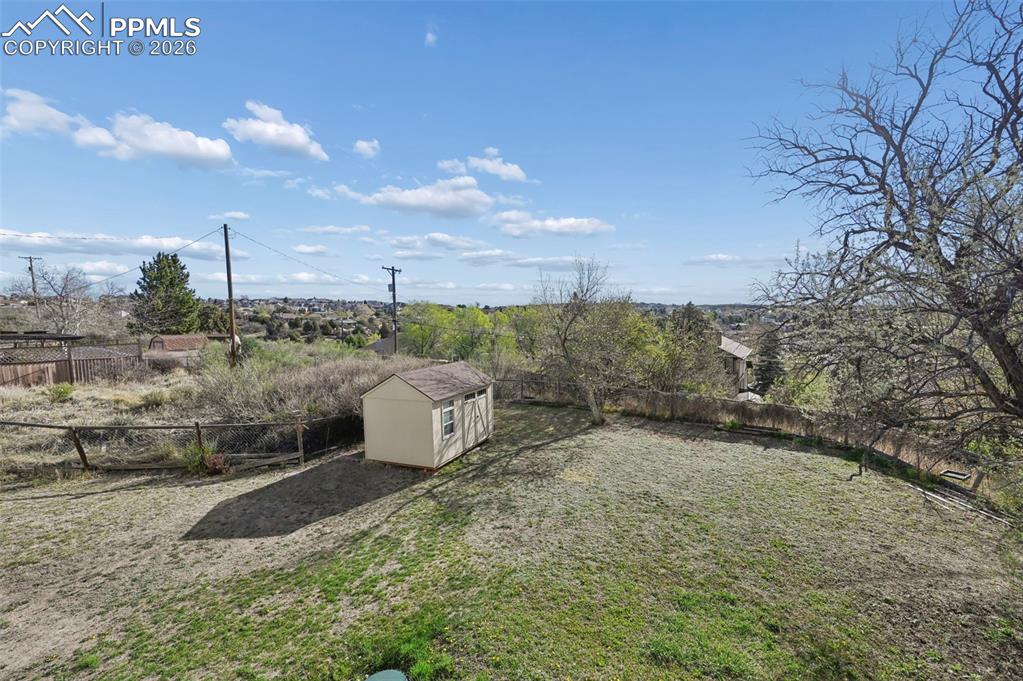 Image 34 of 45: large grassed fenced in backyard with storage shed.