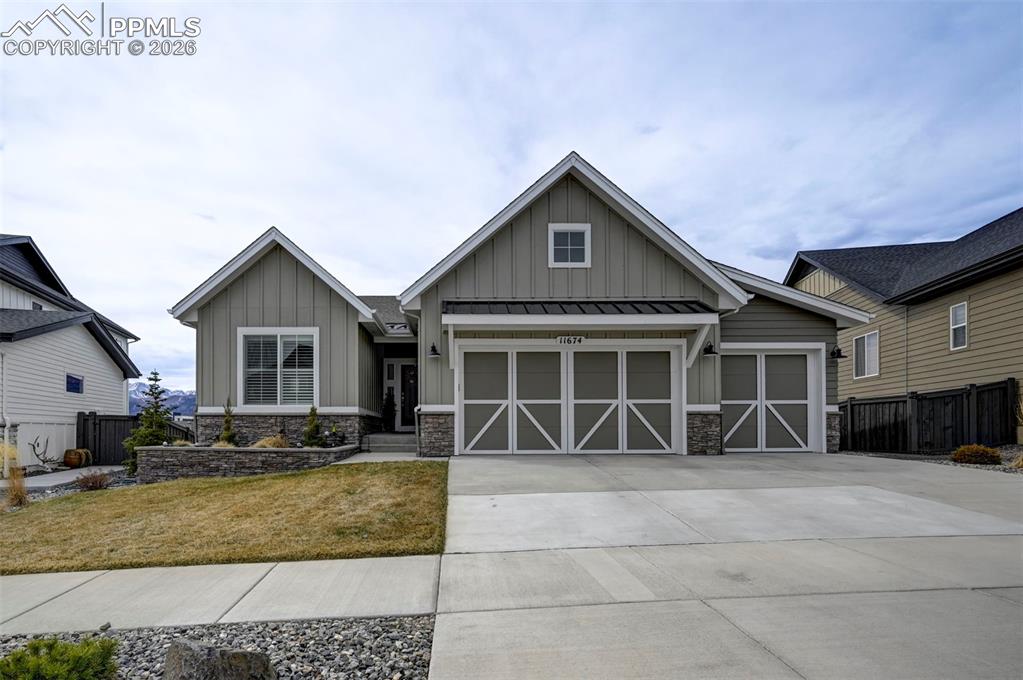 Caption: Craftsman house featuring board and batten siding, stone siding, concrete driveway, and a garage