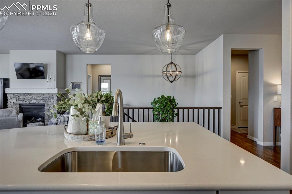 Image 13 of 41: Kitchen featuring a stone fireplace, open floor plan, dark wood-style floor