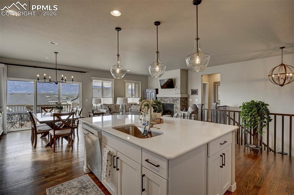 Image 15 of 41: Kitchen with a chandelier, a fireplace, open floor plan, white cabinets, an