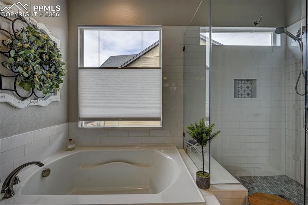 Image 19 of 41: Bathroom featuring a garden tub, a shower stall, and a textured wall