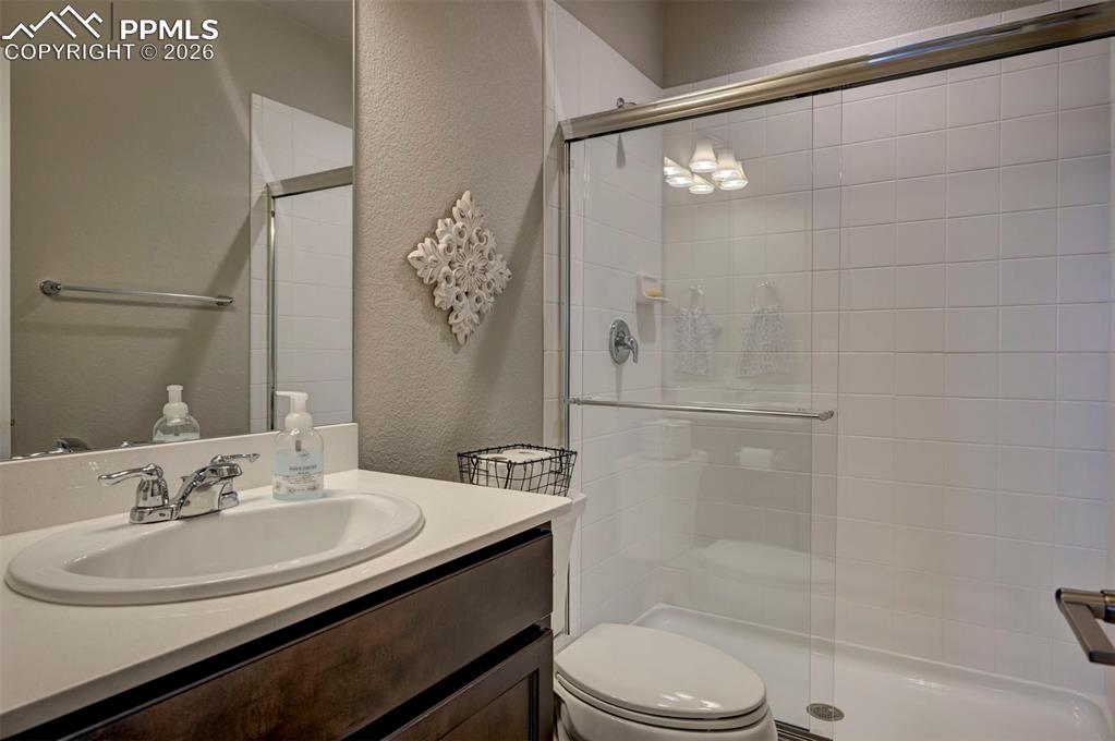 Image 28 of 41: Full bathroom with a textured wall, vanity, and a stall shower