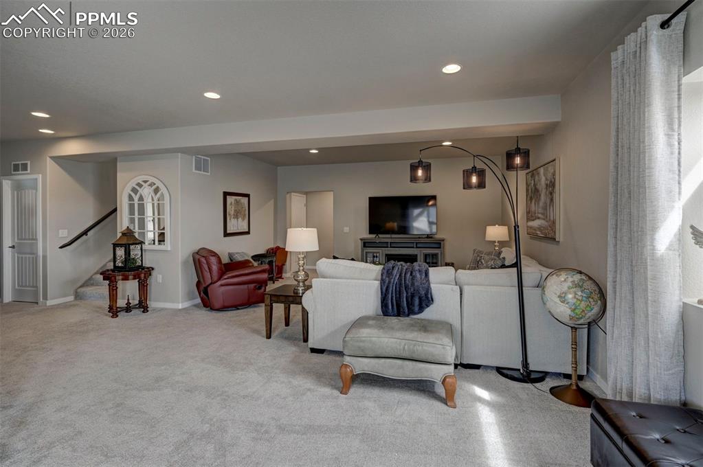 Image 29 of 41: Living area with recessed lighting and light carpet
