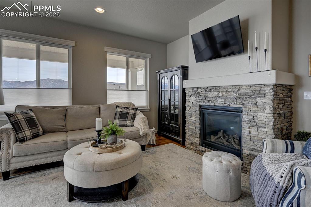 Image 9 of 41: Living area featuring wood finished floors, a stone fireplace, and recessed
