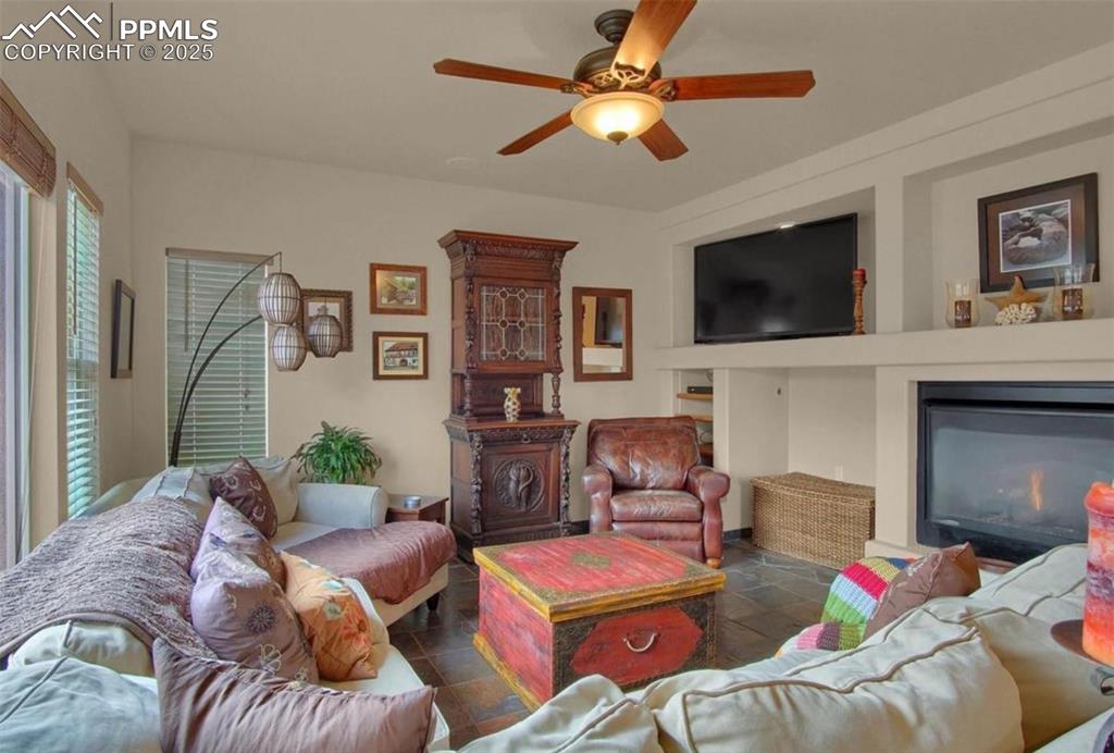 Image 11 of 42: Living room with ceiling fan and a lit fireplace