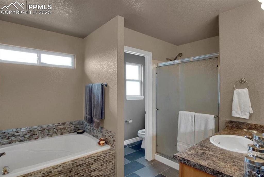 Image 25 of 42: Full bath featuring a textured ceiling, toilet, and a shower stall