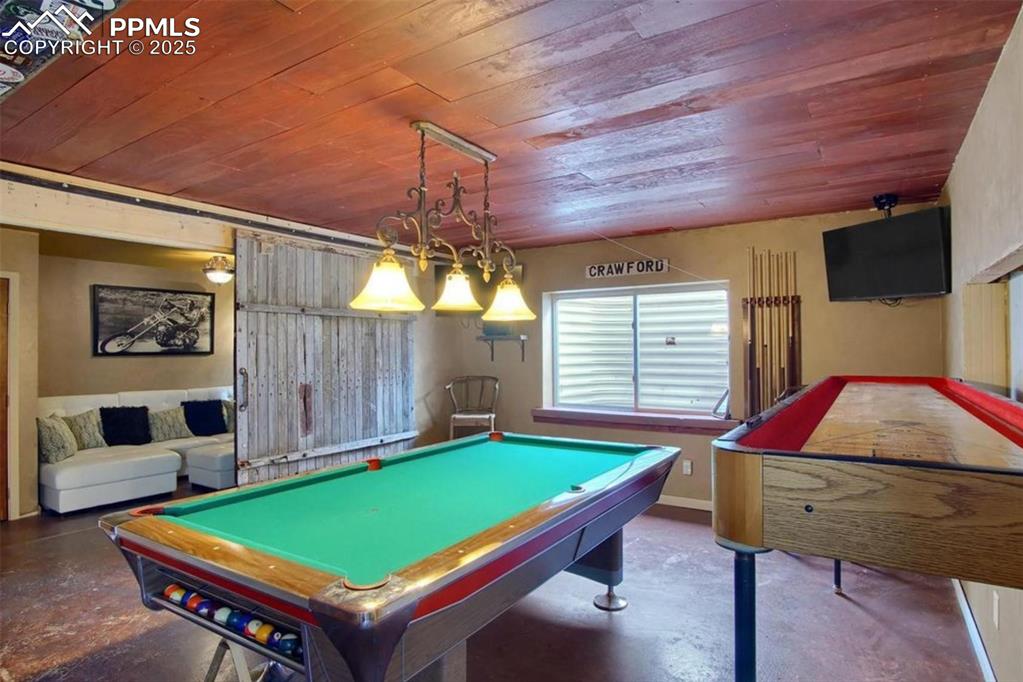 Image 29 of 42: Recreation room with concrete floors, billiards, and wood ceiling