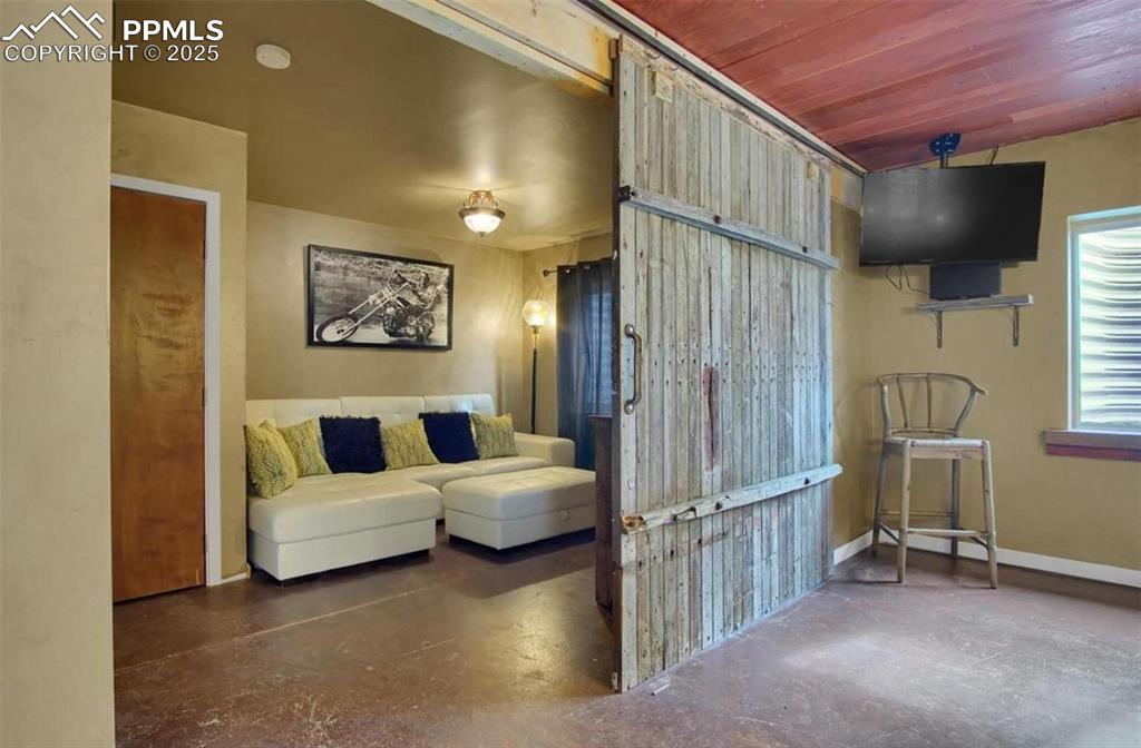 Image 30 of 42: Sitting room with baseboards and concrete flooring