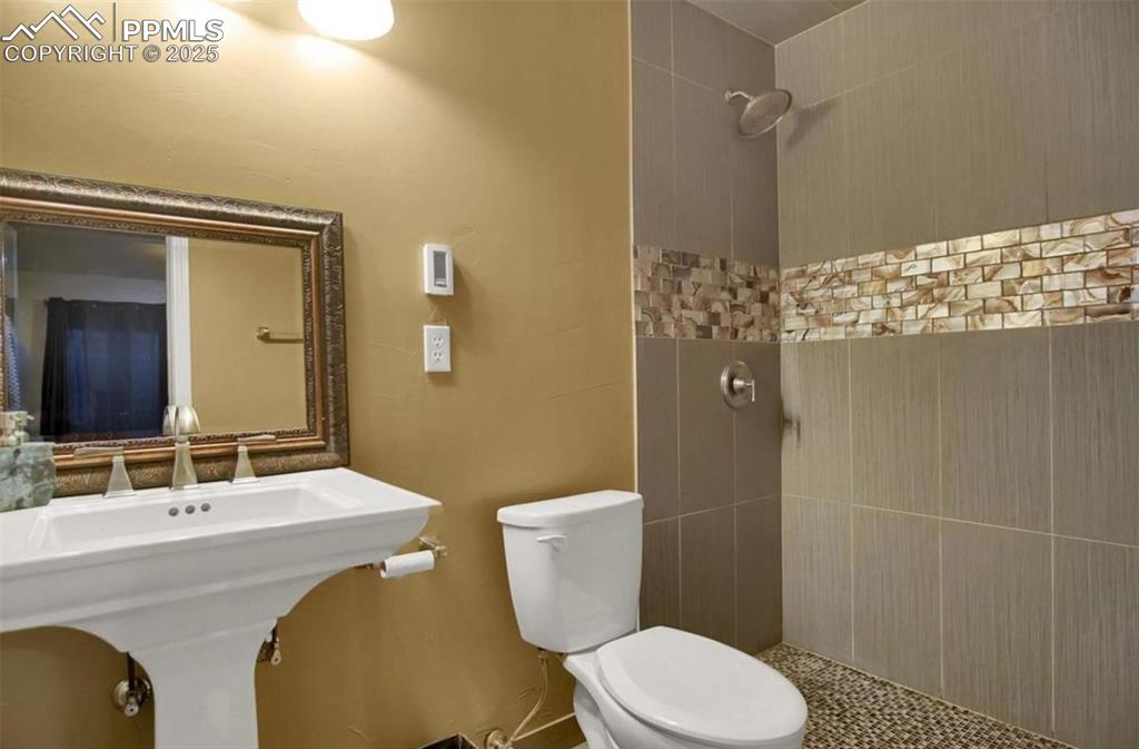 Image 33 of 42: Full bath with a tile shower and toilet