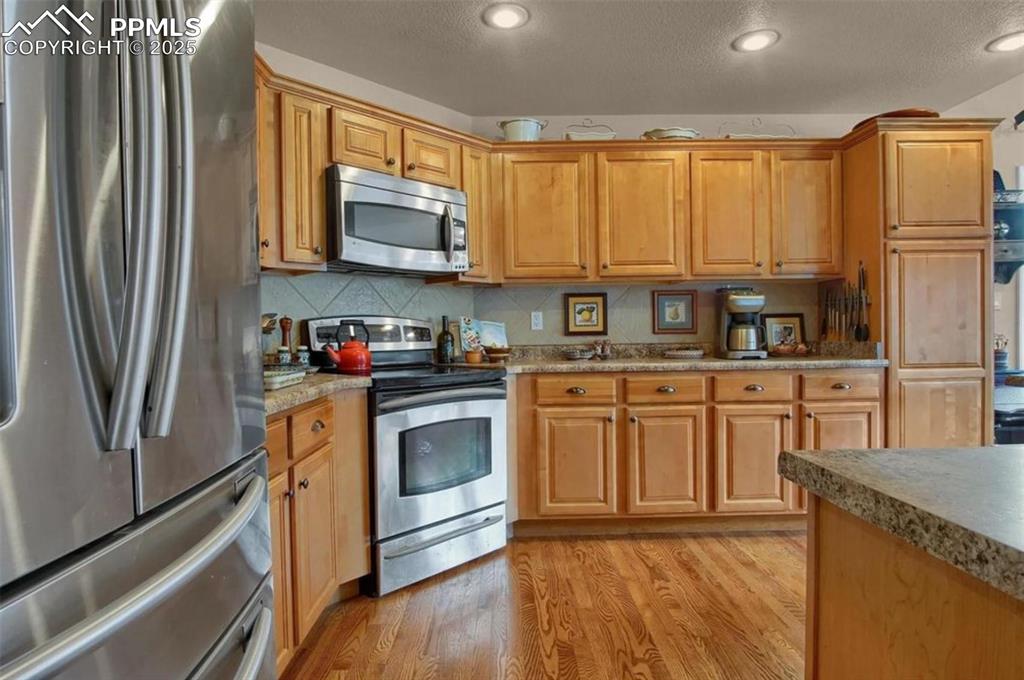 Image 5 of 42: Kitchen featuring a textured ceiling, appliances with stainless steel finis
