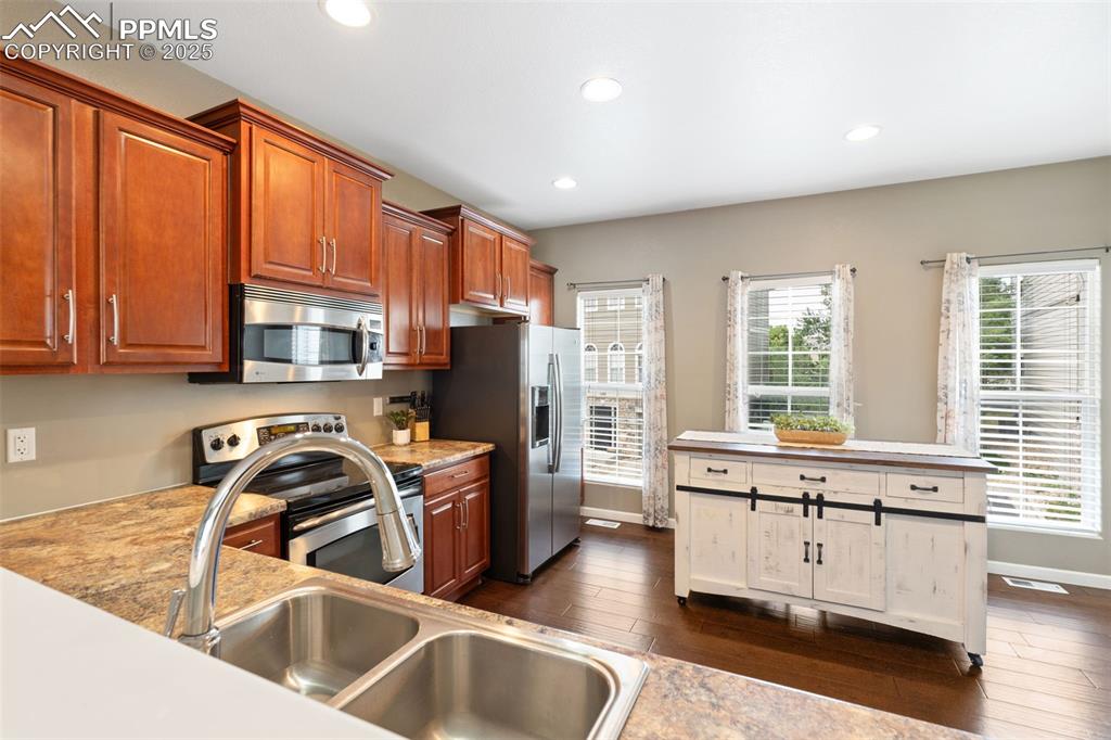 Image 10 of 35: Kitchen with stainless steel appliances, dark wood finished floors, recesse