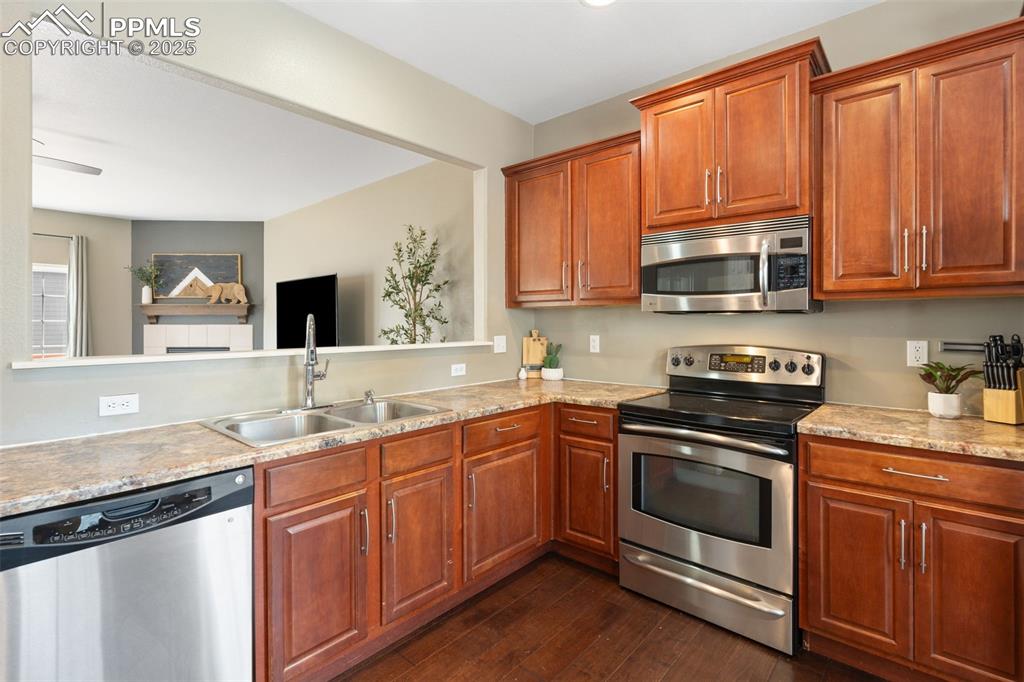 Image 12 of 35: Kitchen featuring stainless steel appliances, dark wood-style floors, and b