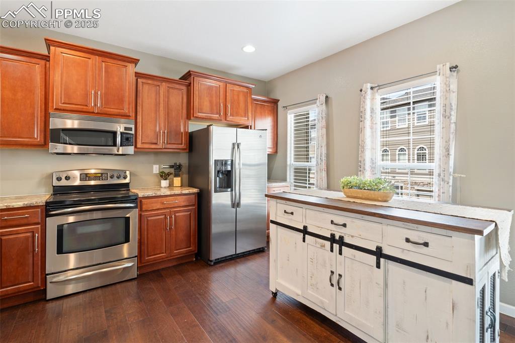Image 13 of 35: Kitchen featuring stainless steel appliances, dark wood-style flooring, bro