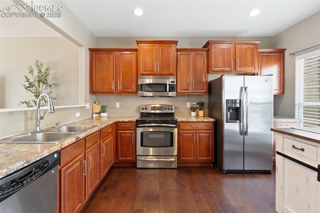 Image 14 of 35: Kitchen featuring appliances with stainless steel finishes, dark wood-style