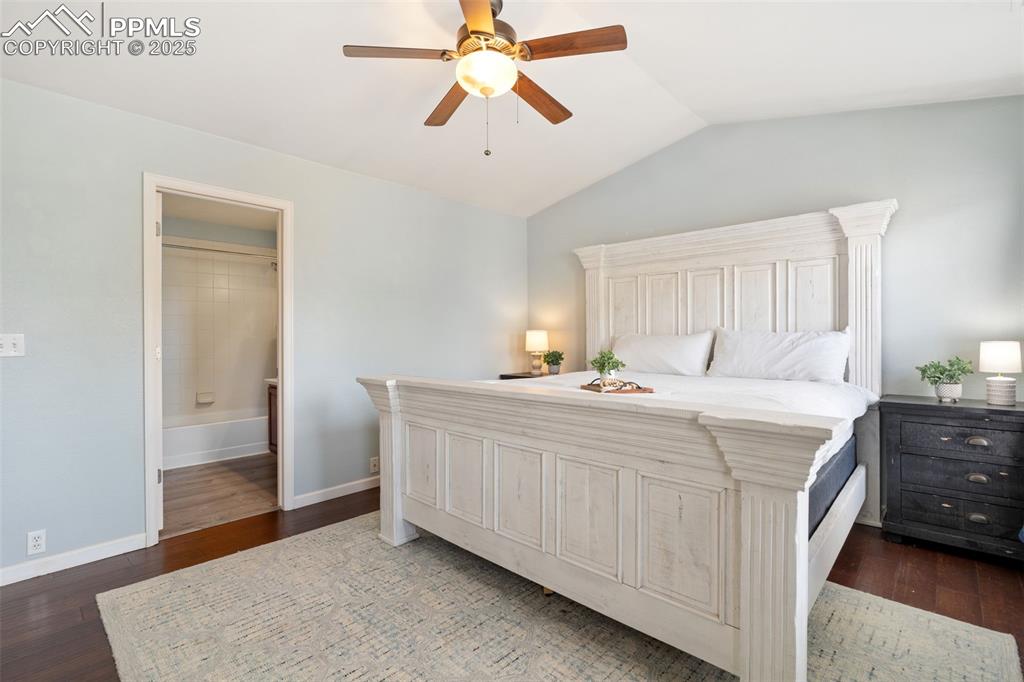 Image 18 of 35: Bedroom with lofted ceiling, dark wood-type flooring, a ceiling fan, and en