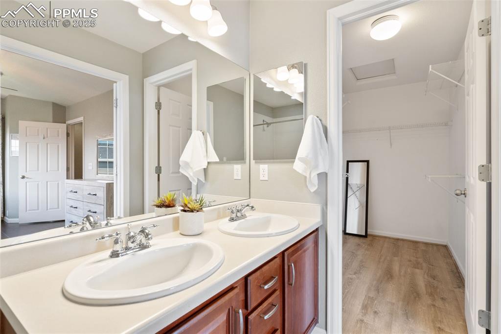 Image 21 of 35: Full bath featuring double vanity, wood finished floors, and a walk in clos