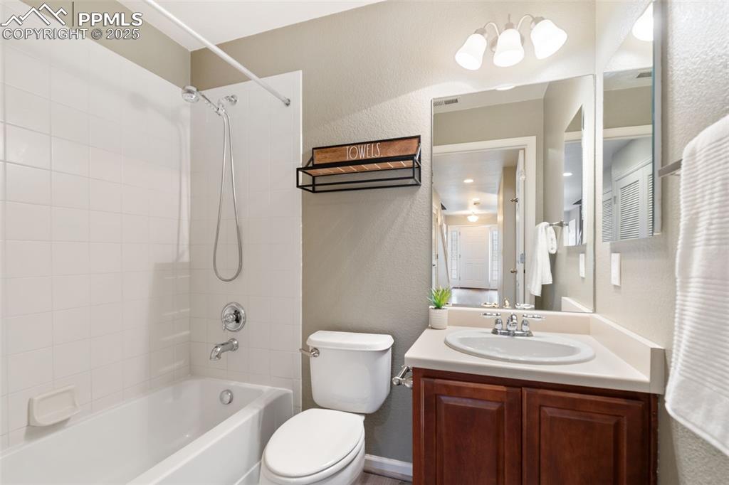 Image 28 of 35: Full bath with a textured wall, shower / washtub combination, and vanity